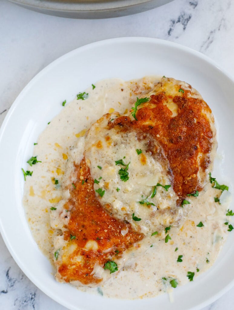 Close up of a creamy caesar sauce on a crispy baked chicken breast.