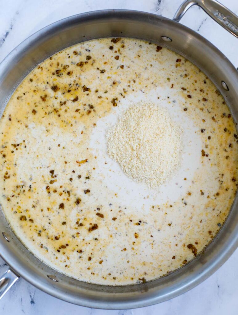 Parmesan added to a sauce in a skillet.