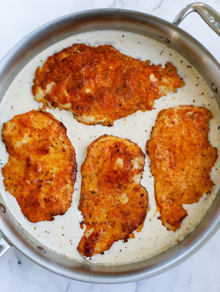 Adding crispy chicken to a skillet of sauce.