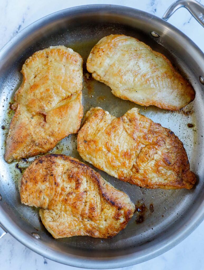 Pan frying chicken breasts in a skillet.