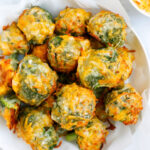 Overhead shot of cheesy broccoli bites on a white bowl.