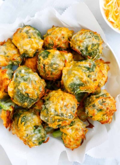 Overhead shot of cheesy broccoli bites on a white bowl.