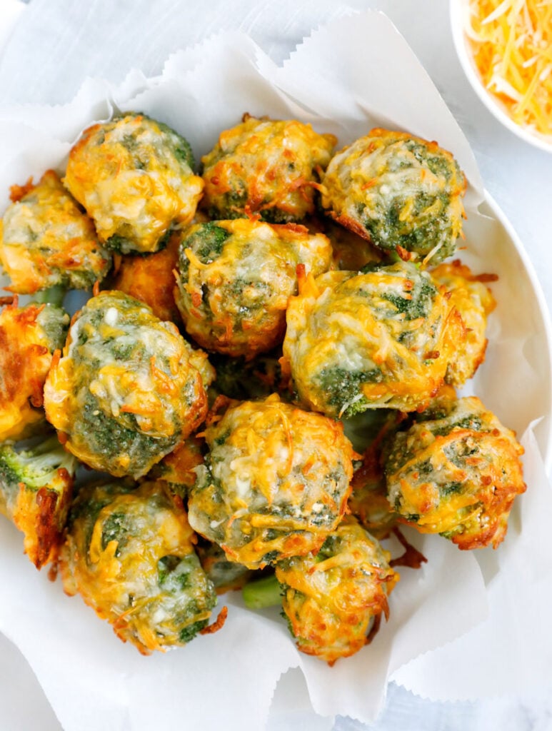 Overhead shot of cheesy broccoli bites on a white bowl.