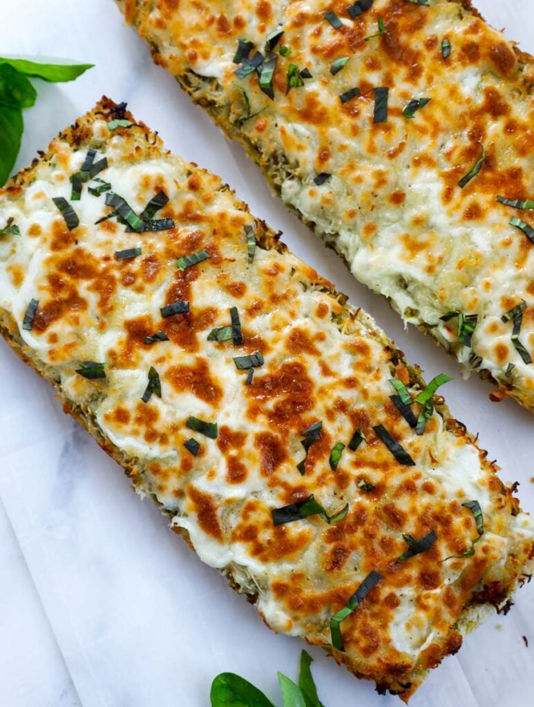 Top down shot of two cheesy breadsticks on a white table top.