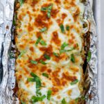 Top down shot of cheesy pesto breadstick surrounded with foil.