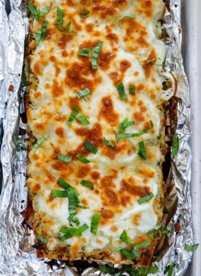 Top down shot of cheesy pesto breadstick surrounded with foil.