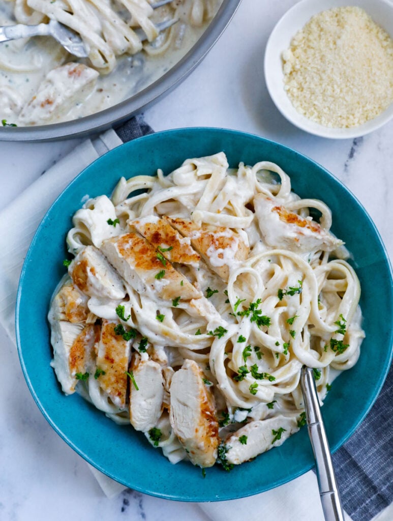 Overhead shot of creamy chicken alfredo pasta on a blue plate. 