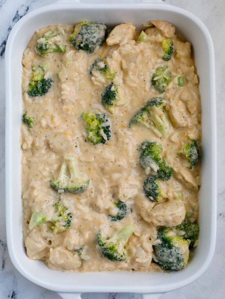 A white casserole dish with chicken, broccoli, and rice in a sauce.
