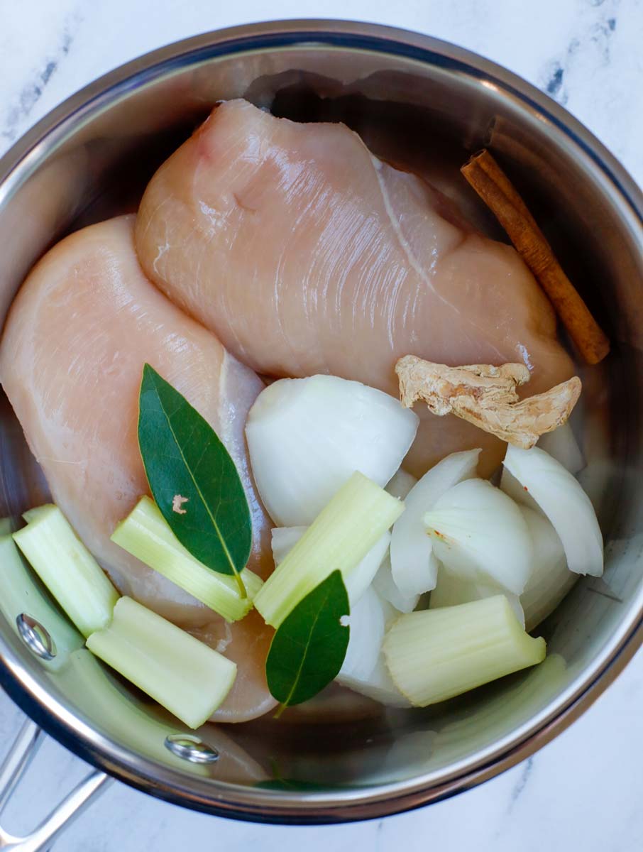 A pot with chicken and aromatics.