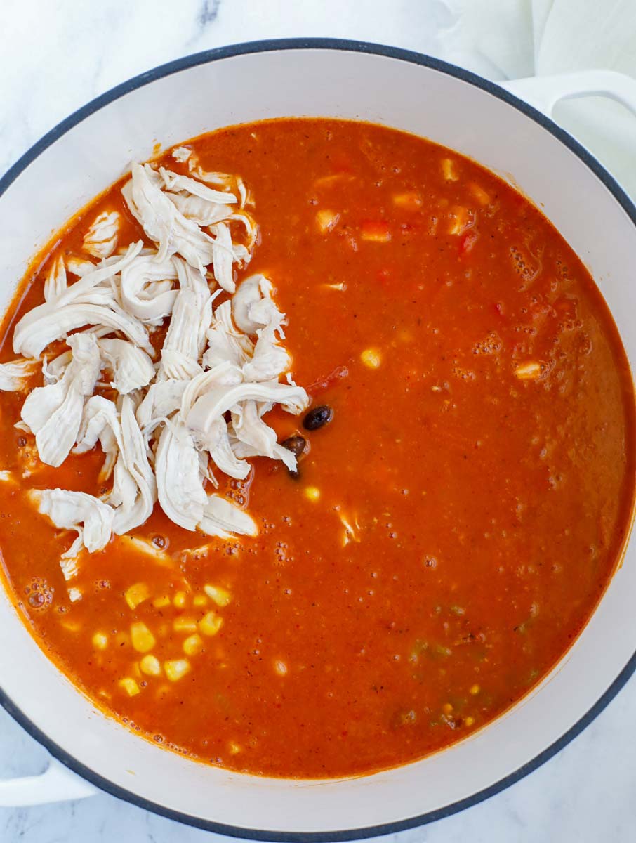 Adding shredded chicken, black beans, corn and green chilies into the pot.