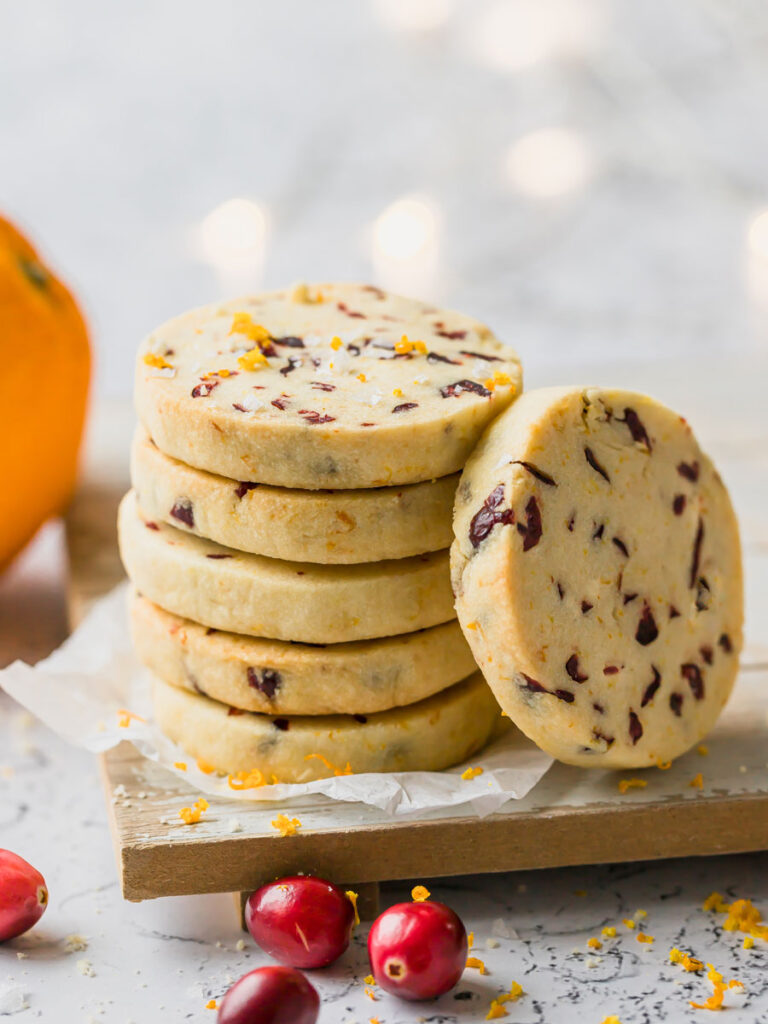 A stack of shortbread cookies surrounded by cranberries. 