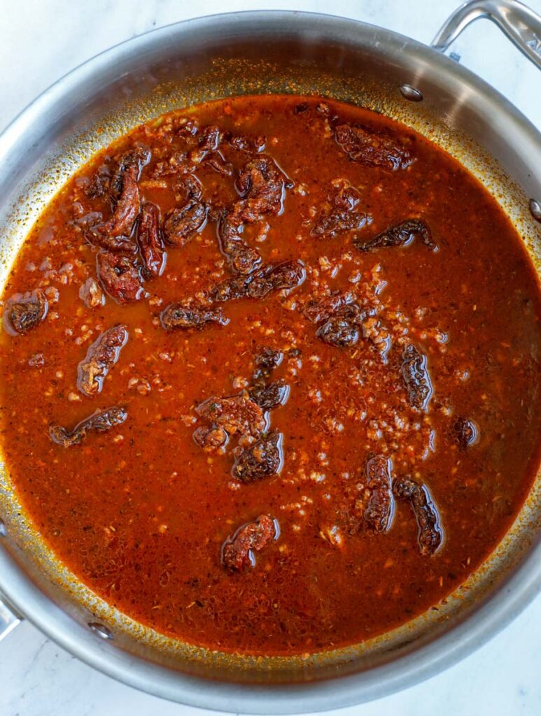 Chipotle pepper sauce, chicken broth and sundried tomatoes added into a skillet.