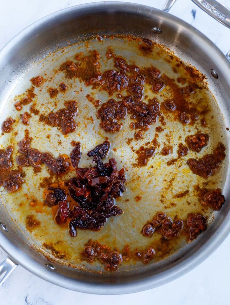 A skillet with sautéd the garlic and spices.