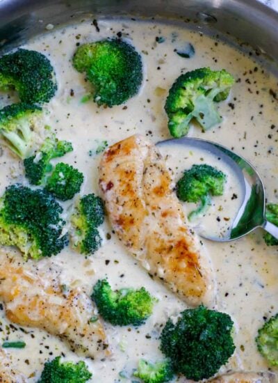 A spoon dipping into a pot of creamy chicken broccoli.
