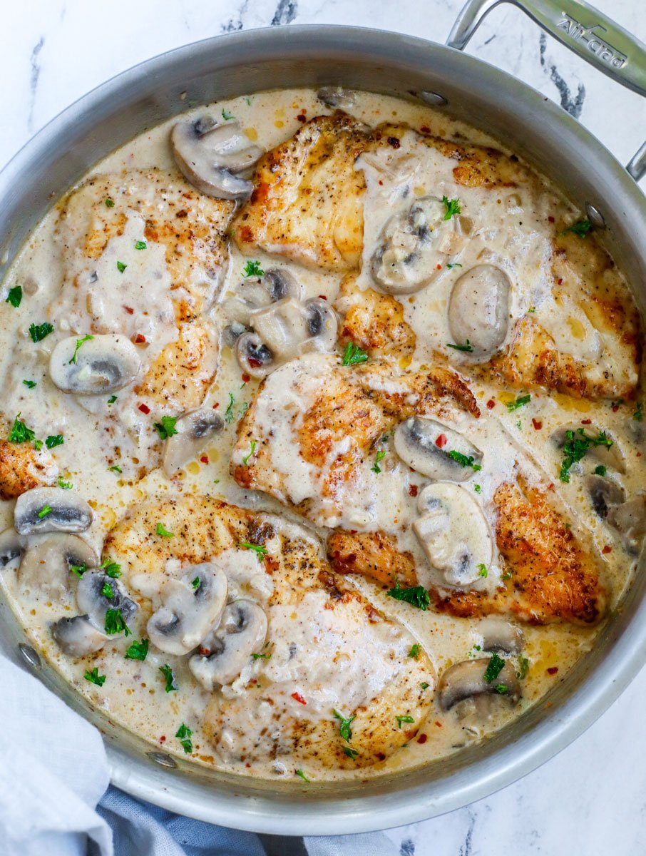 Top down view of creamy mushroom chicken in a silver pot. 