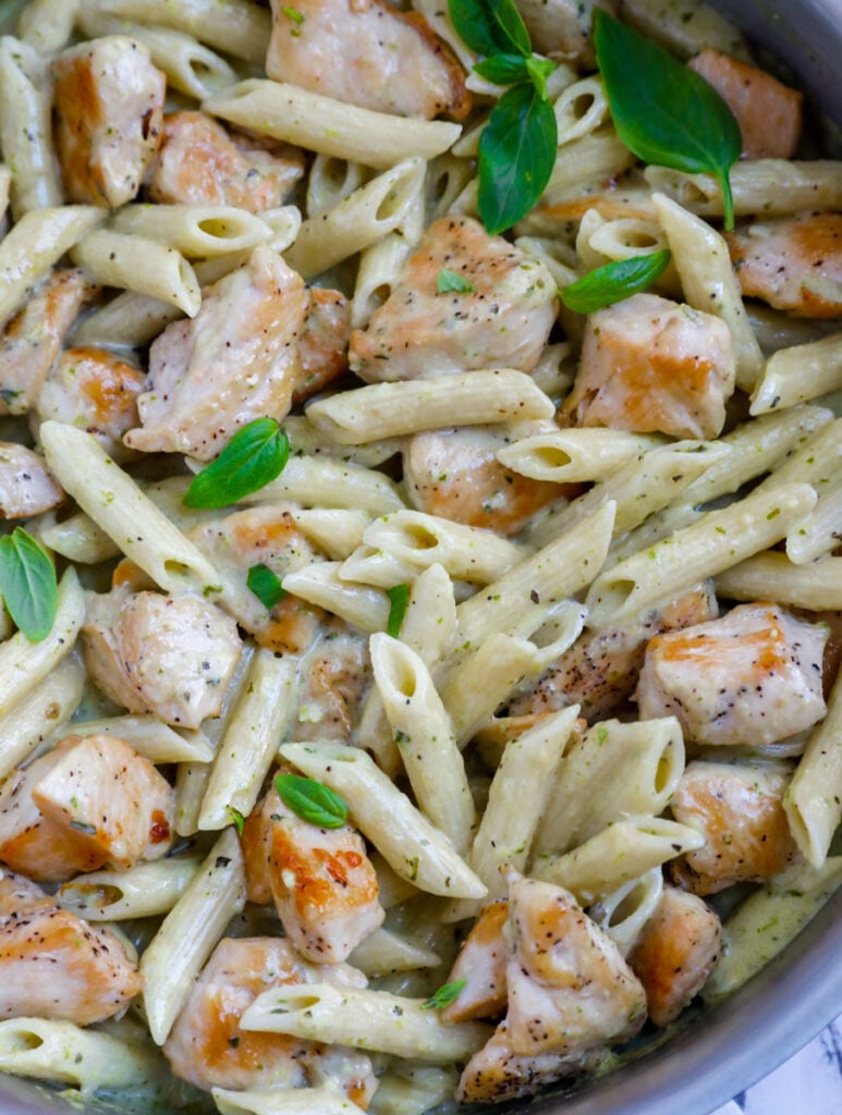 Close up of creamy pesto chicken pasta in a pan.