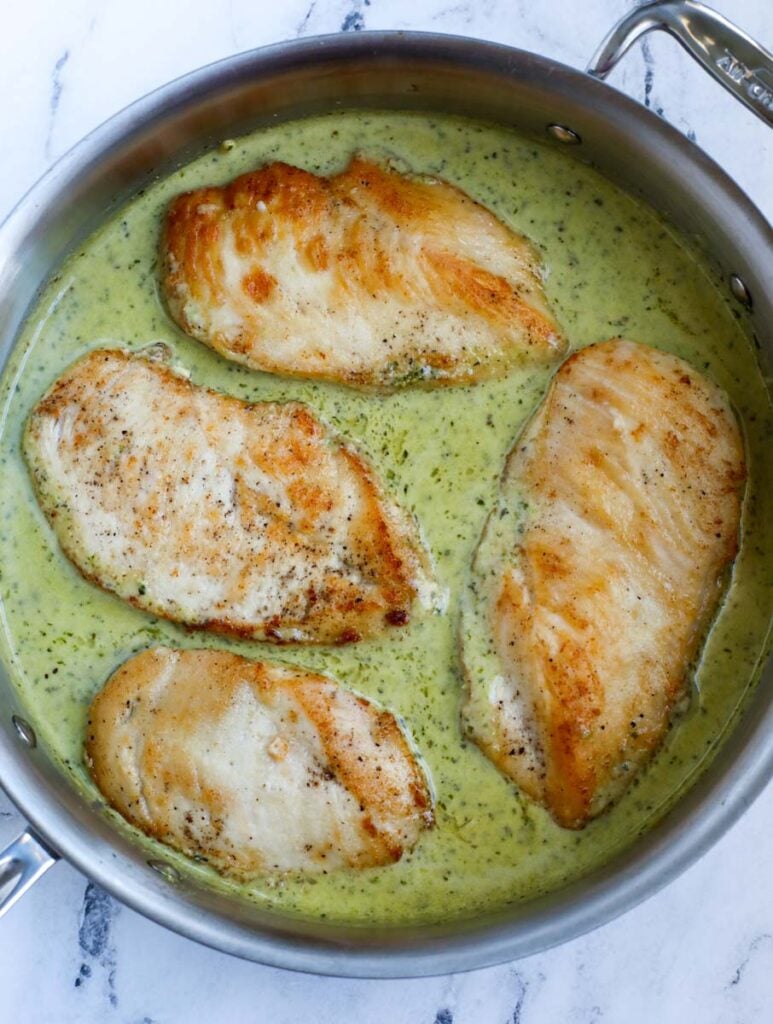 Chicken in pesto sauce in a pan.