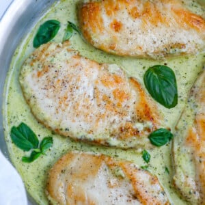 Top down view of creamy pesto chicken in a pan.