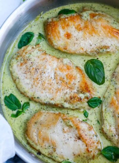 Top down view of creamy pesto chicken in a pan.