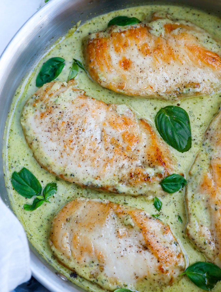 Top down view of creamy pesto chicken in a pan.