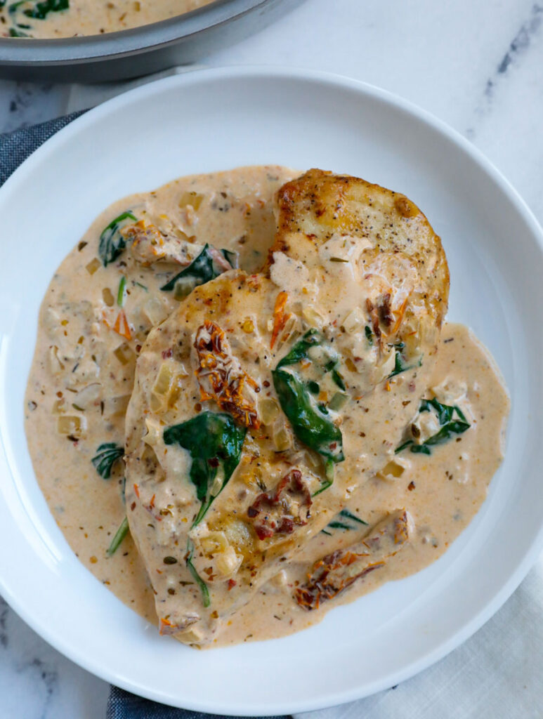 piece of creamy chicken tuscan breast on a white plate