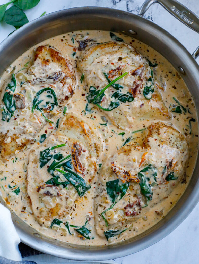 Top down view of tuscan chicken in a silver pan.
