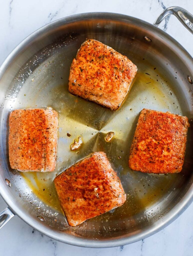 Pan searing the salmon in a pan.