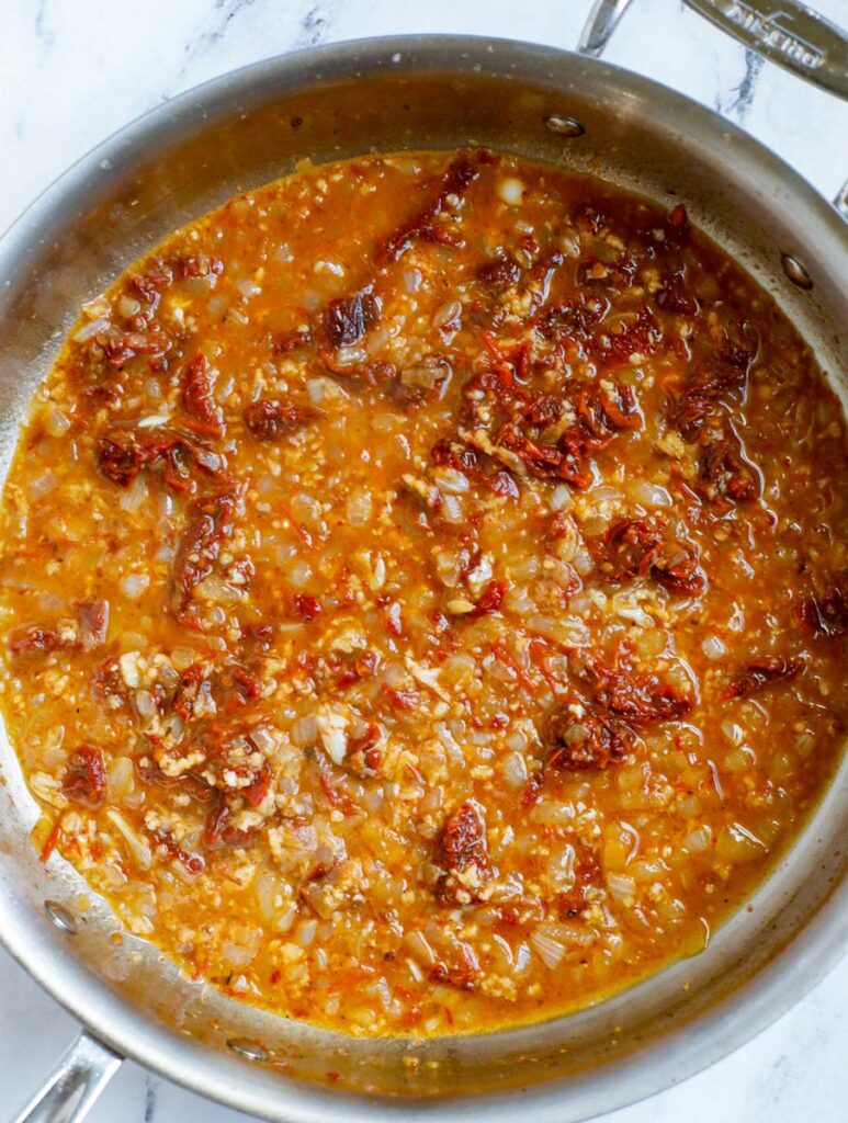 Garlic and herbs in a pot with broth