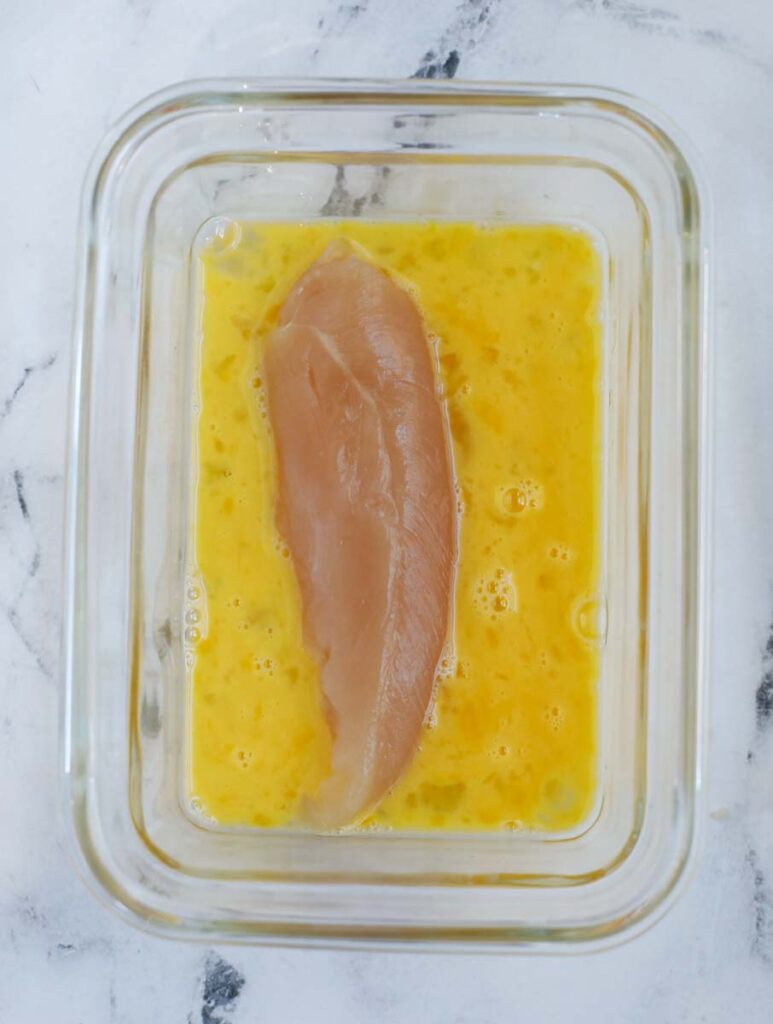 Chicken tender in egg wash.