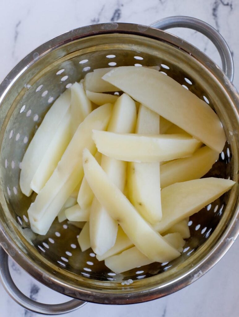 Draining potato slices in a colander.