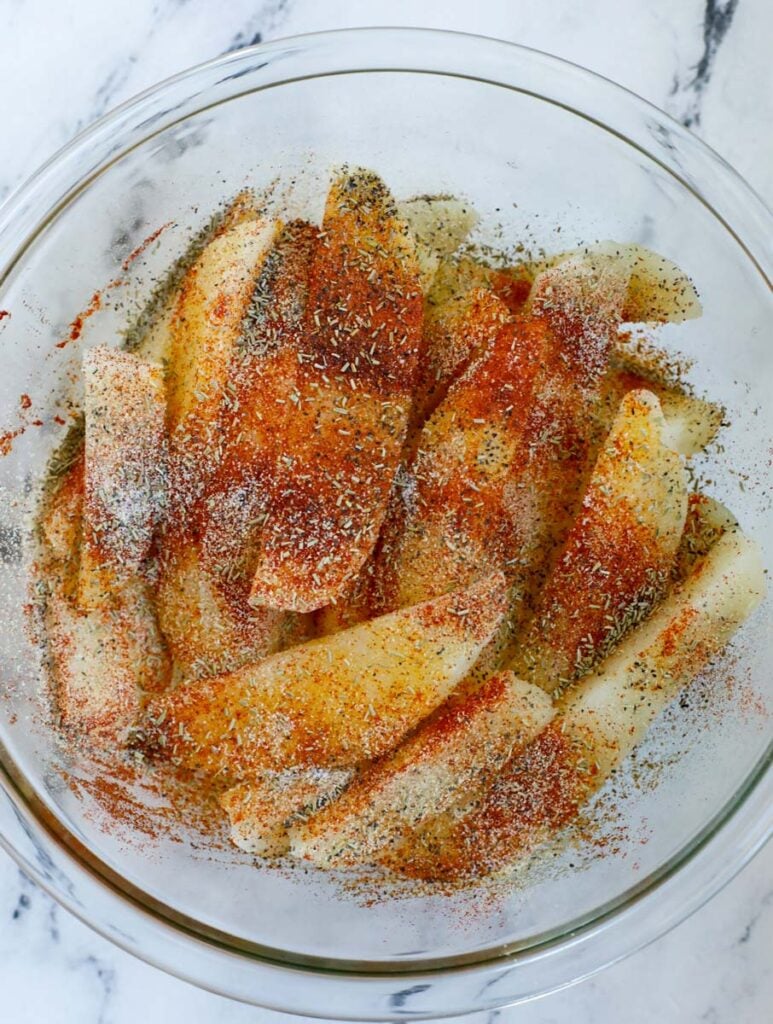 Potato slices and seasoning in a bow.