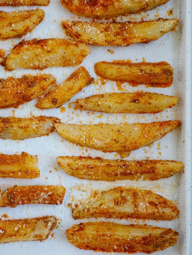 Overhead view of potato wedges on a tray before baking.