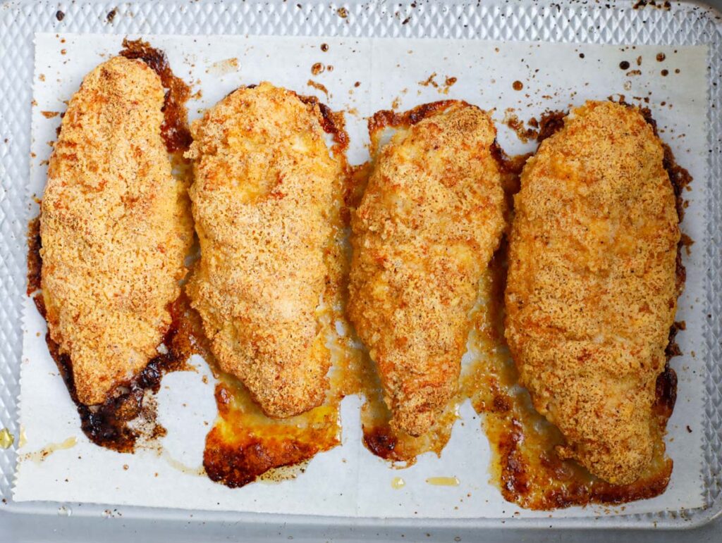 Top down shot of baked chicken breasts on parhcment.