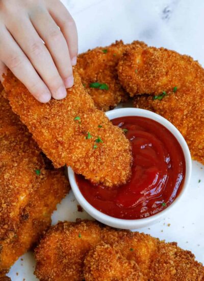 chicken tenders being dipped in ketchup