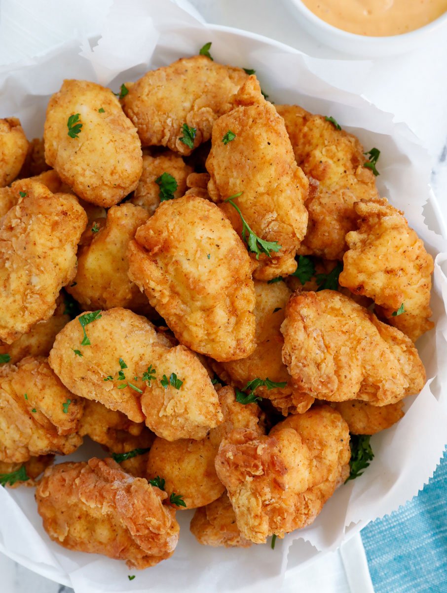 Top down view of homemade chicken nuggets on a plate with dip on the side.