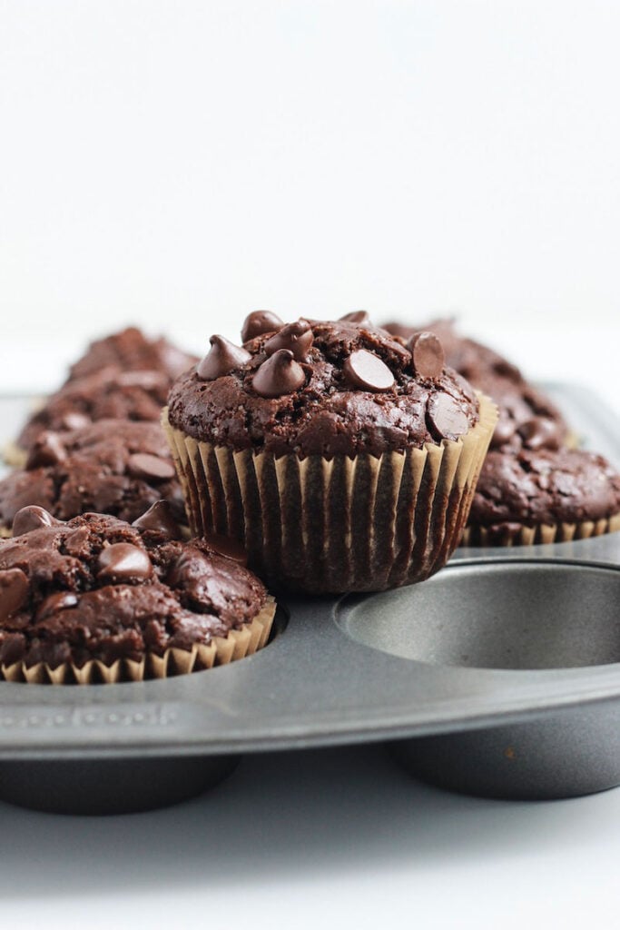 Close up of double chocolate chip muffins on top of a muffin mold. 