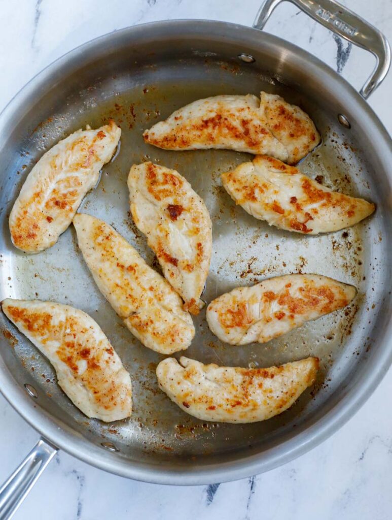 Chicken turning golden in a pan.