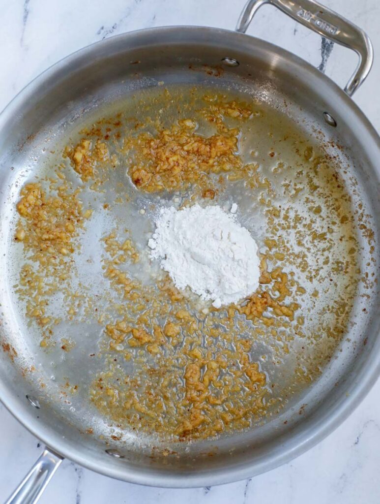 Cooking garlic and seasoning in a pan.