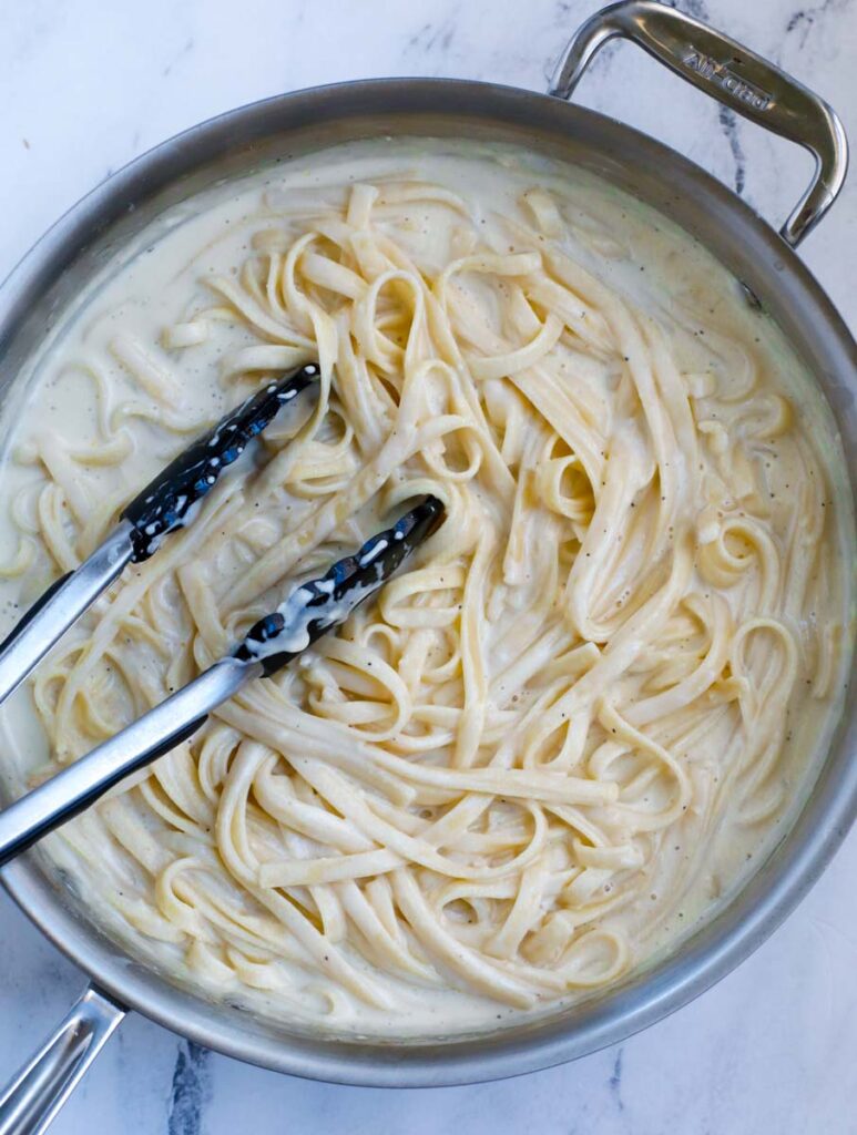 Mixing pasta into the creamy sauce.