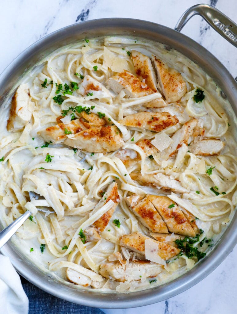 Top down shot of creamy chicken alfredo stirred in a pot. 