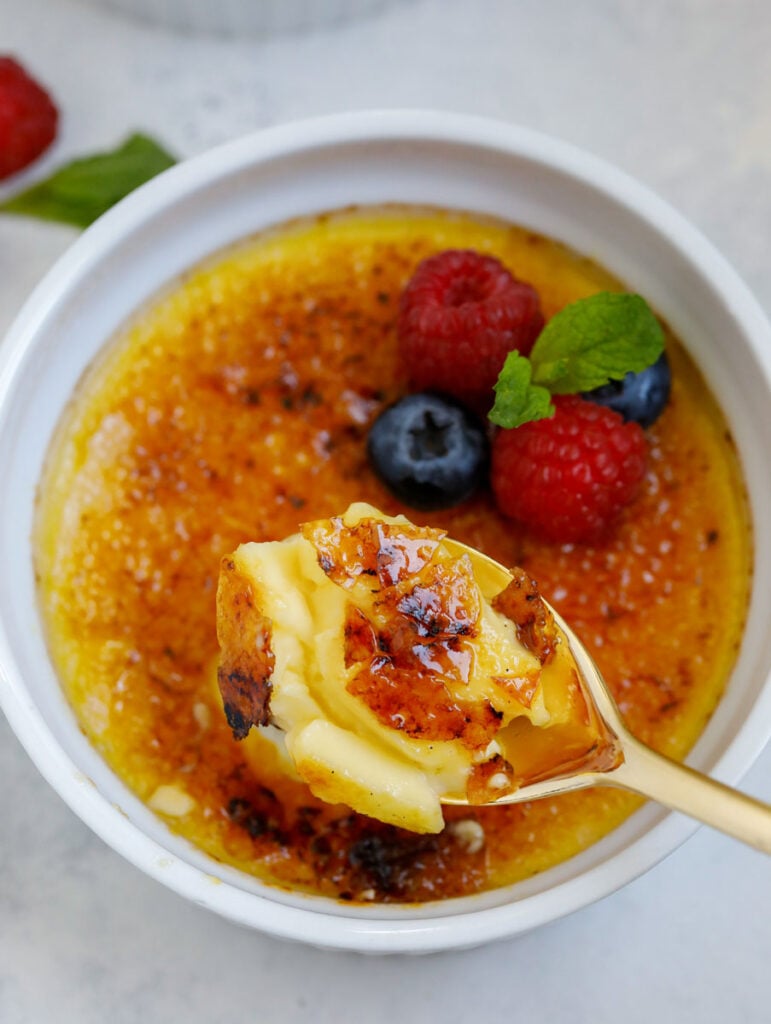 A spoon going into a pot of crème brûlée.