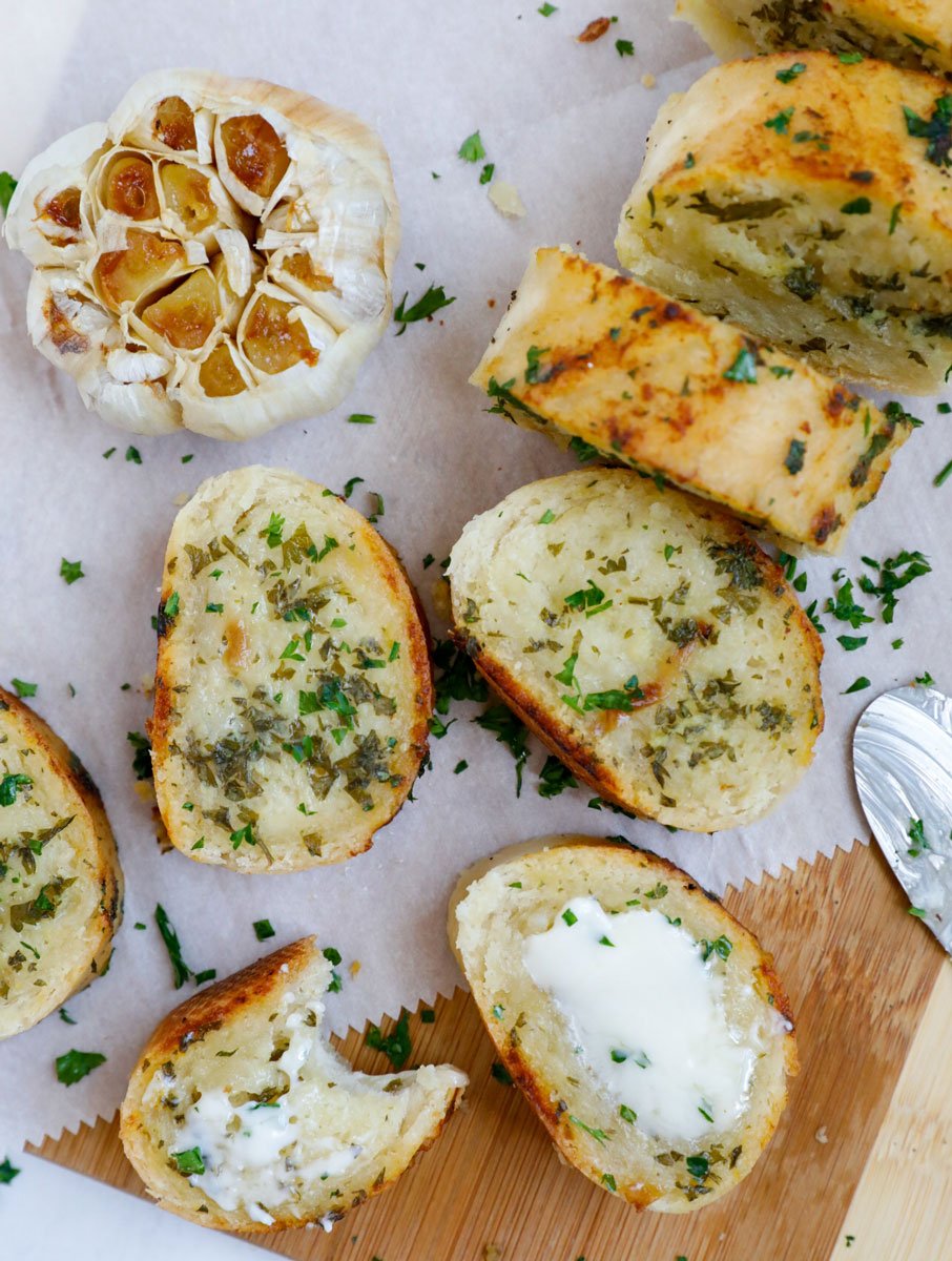 Top down view of sliced garlic bread next to a bulb of garlic.