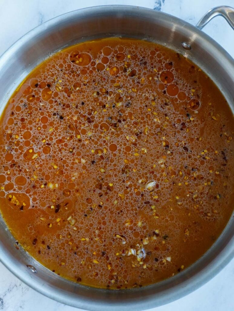 Sauce coming to a boil in a skillet.