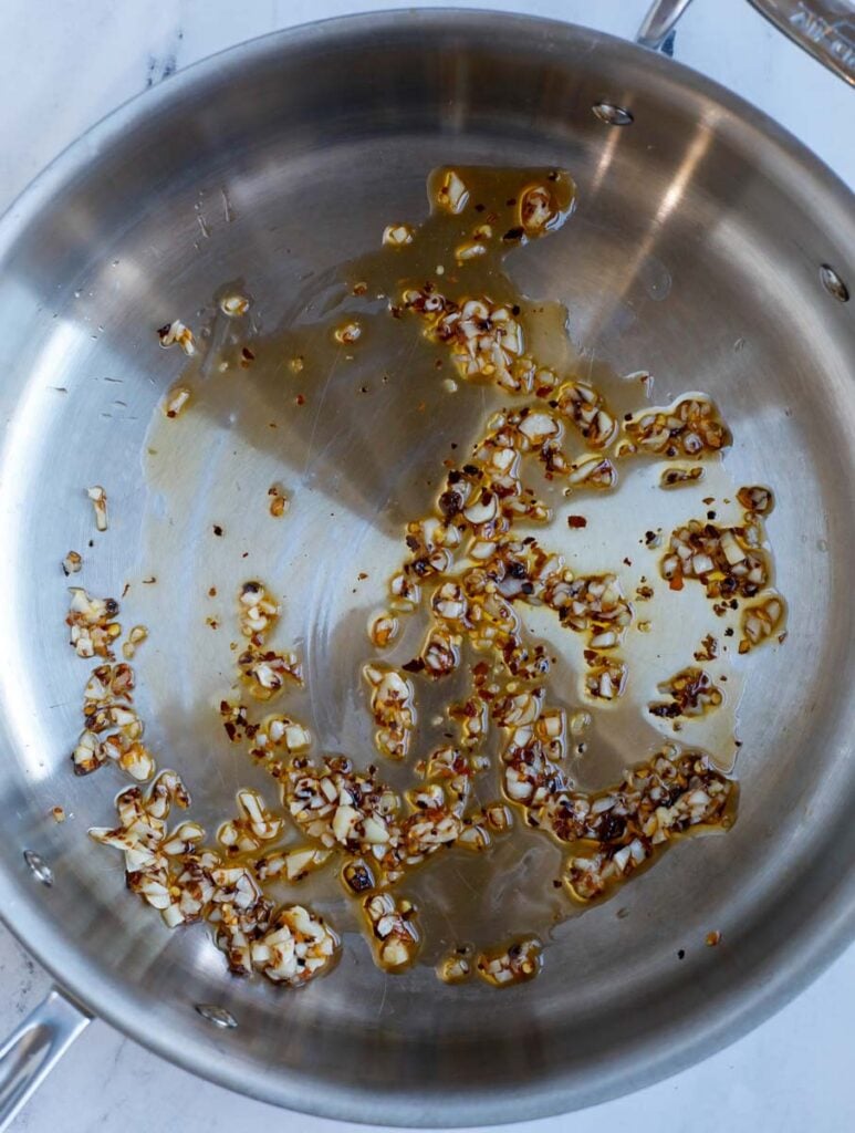 Image of sautéing the garlic and chili flakes in a skillet.