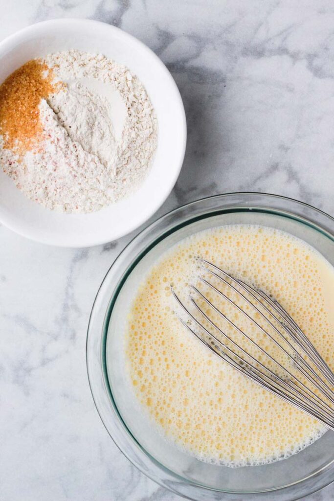 Top down shot of wet ingredients and dry ingredients in glass bowls.