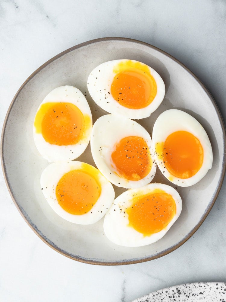 soft boiled eggs cut in half to show the runny yolk center on a plate