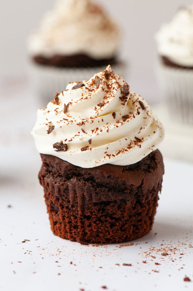 chocolate cupcake with wrap taken off, topped with whipped cream