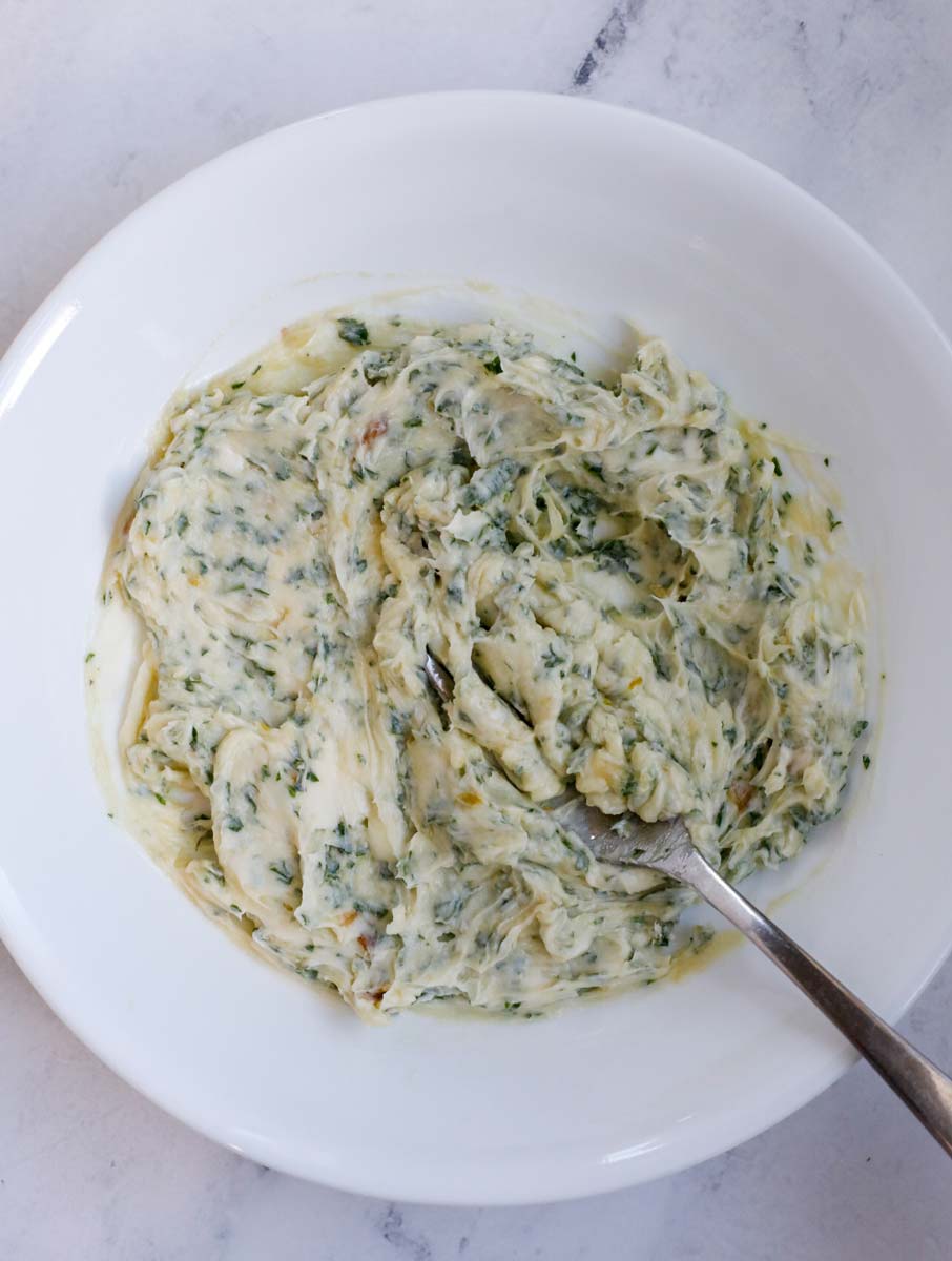 Spoon mixing garlic butter in a bowl.