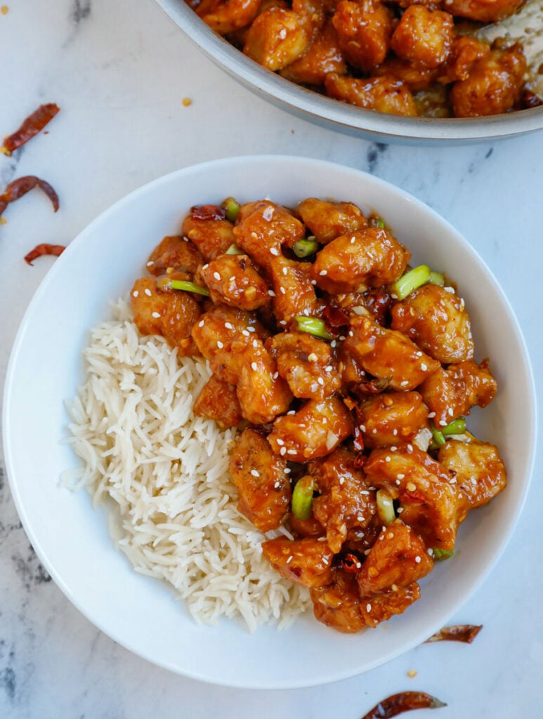 Overhead image of a bowl general tso chicken with a side of rice.