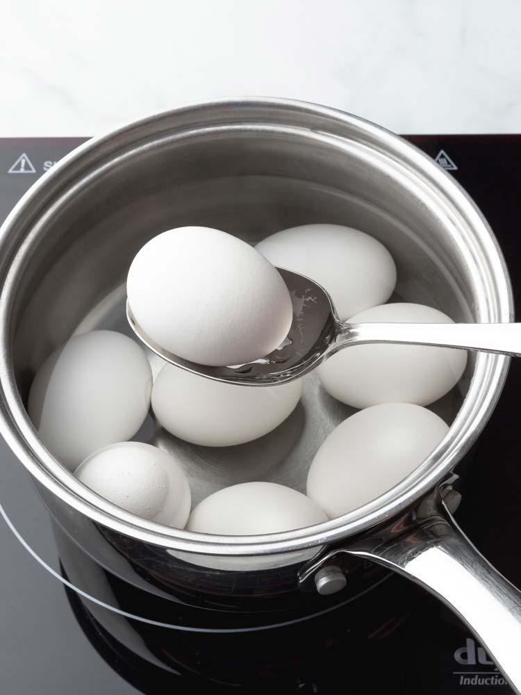 an egg being lifted out of the pot